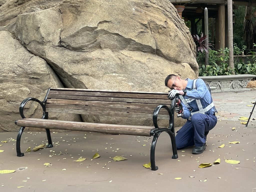 Hong Kong Disney cast member drills wooden bench used in upcycled project