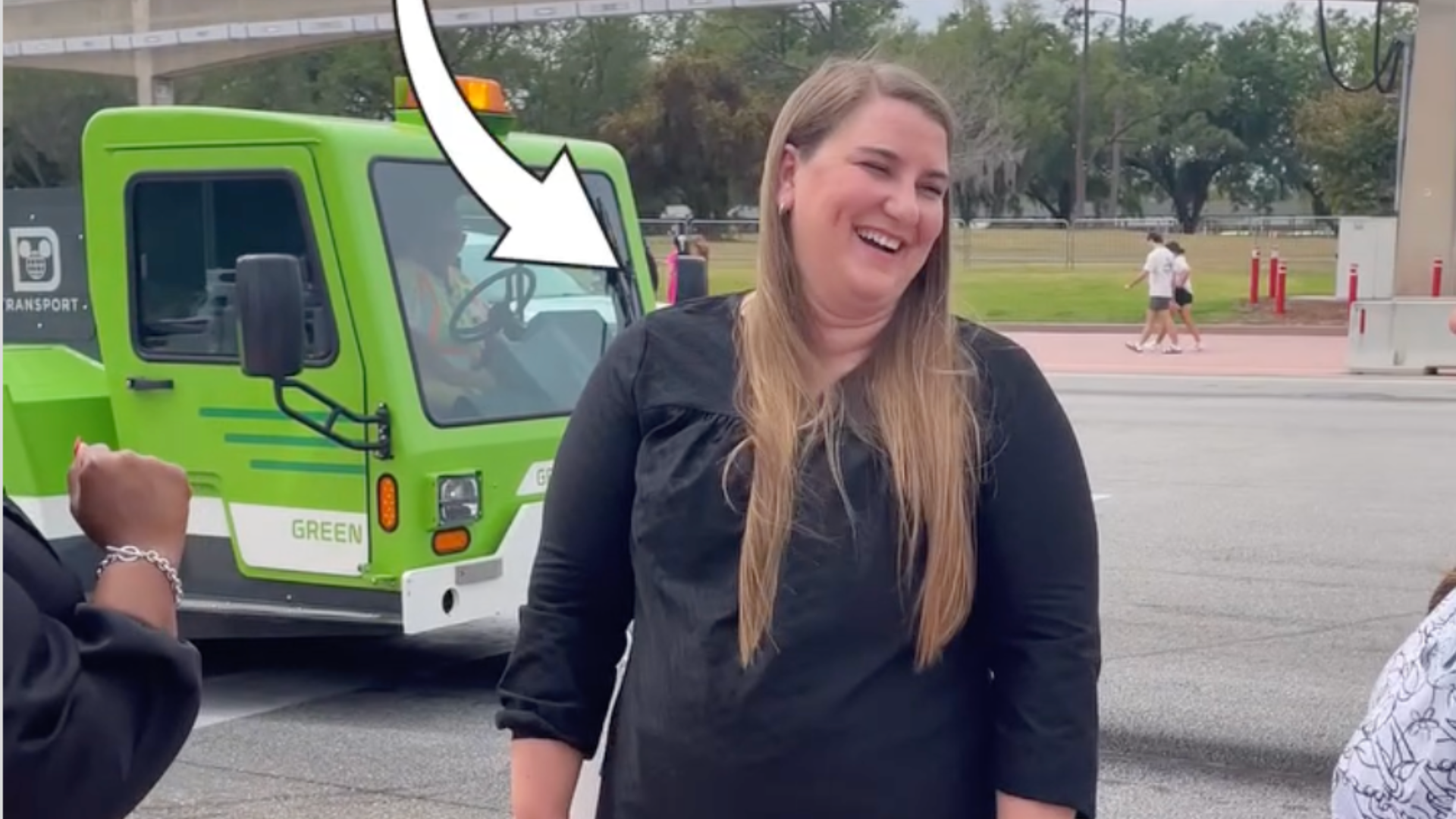 A woman wearing black smiles and an arrow points to her