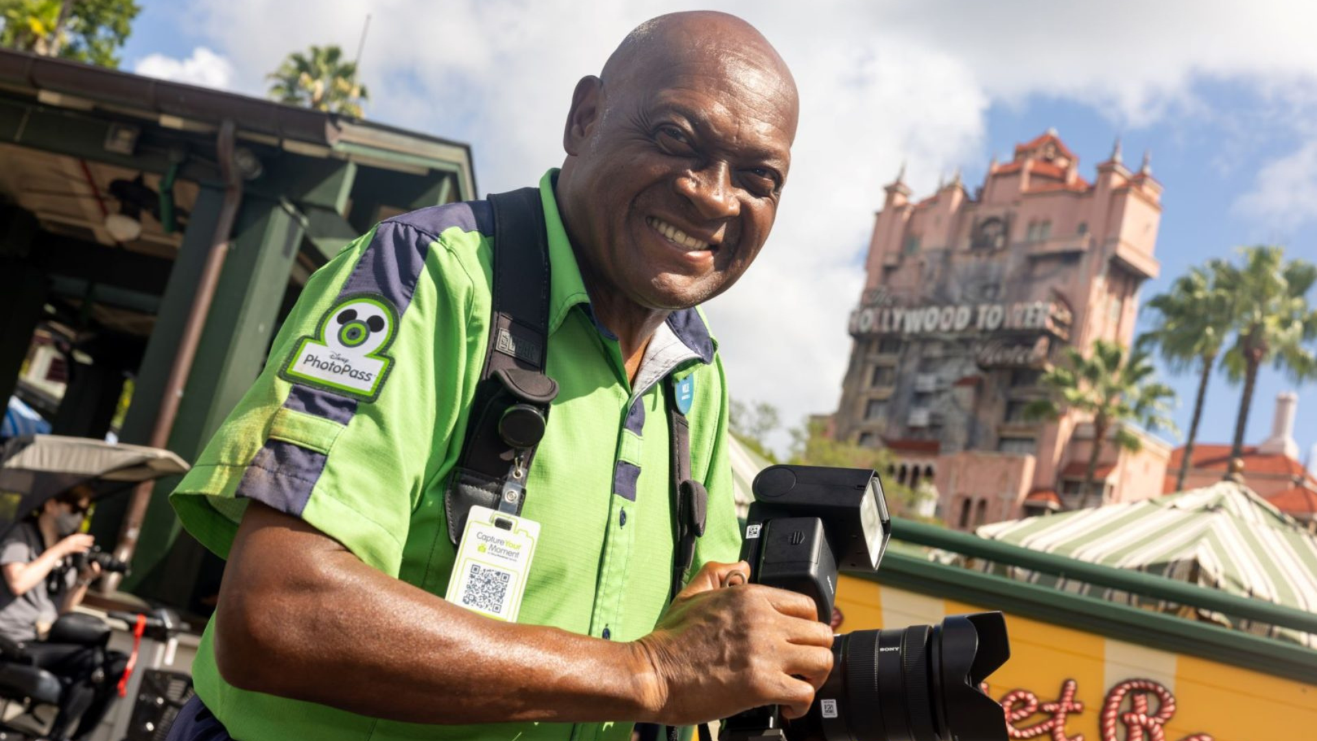 Disney Photopass Cast Member Willie Jackson holds a camera and smiles.