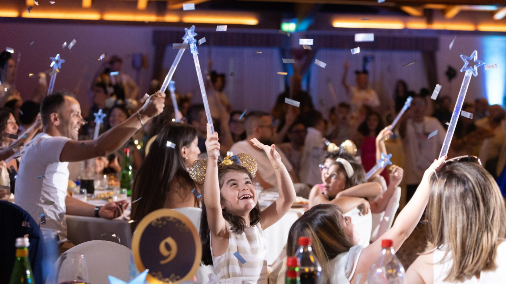 Smiling children hold wands as confetti falls