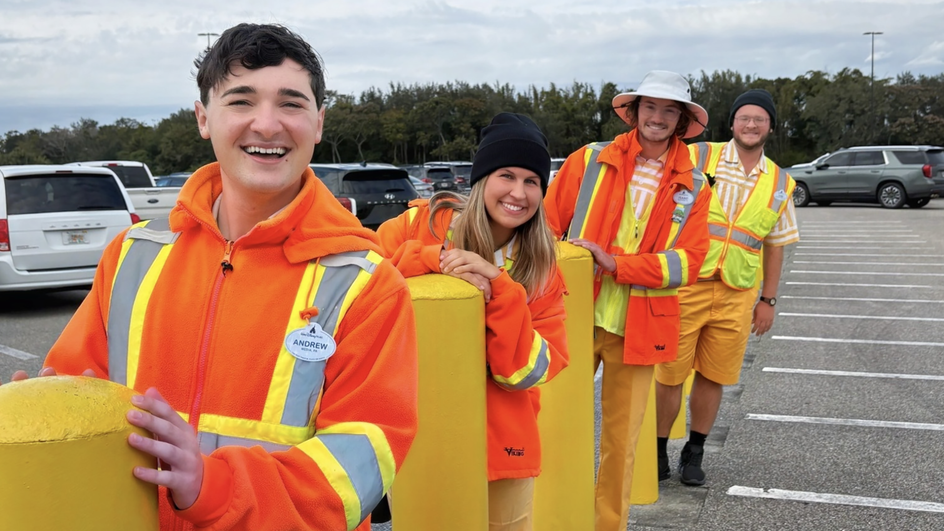 Disney cast members stand in a parking lot and smile