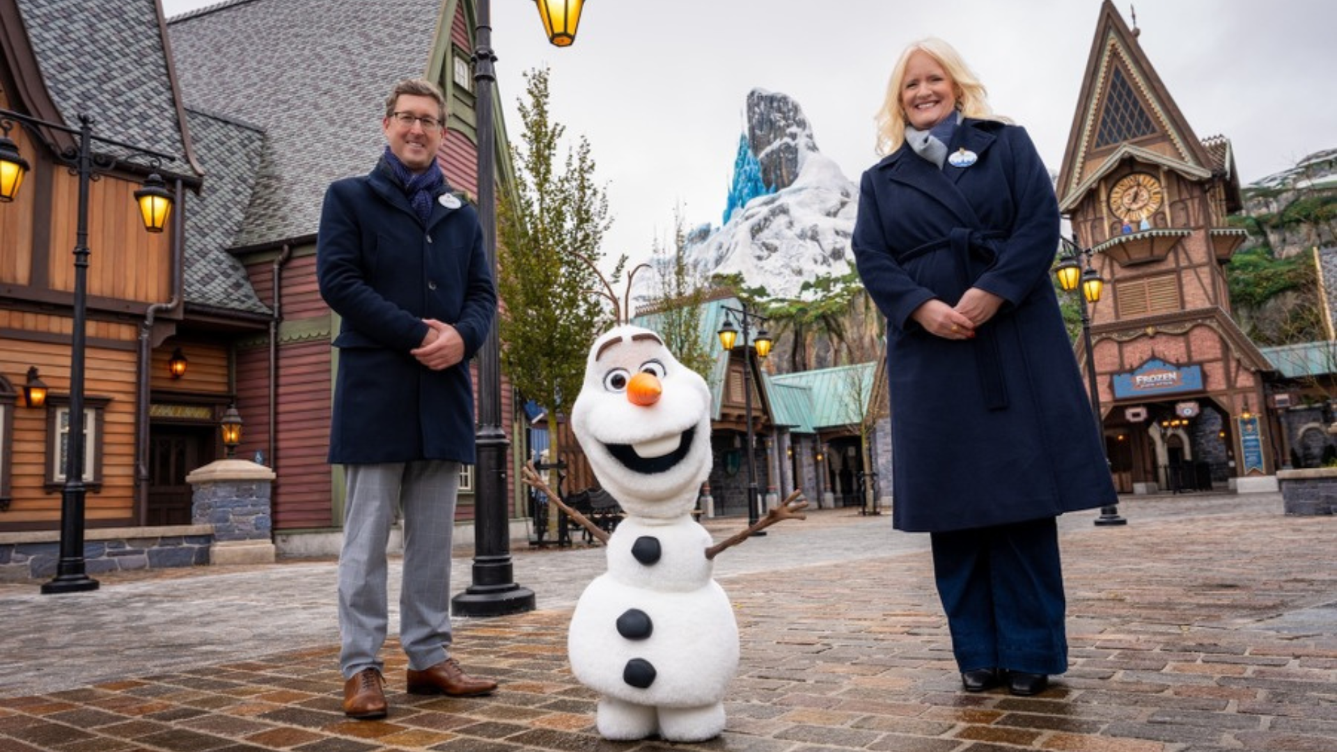 Two people stand on either side of the Olaf robotic character in World of Frozen at Disneyland Paris
