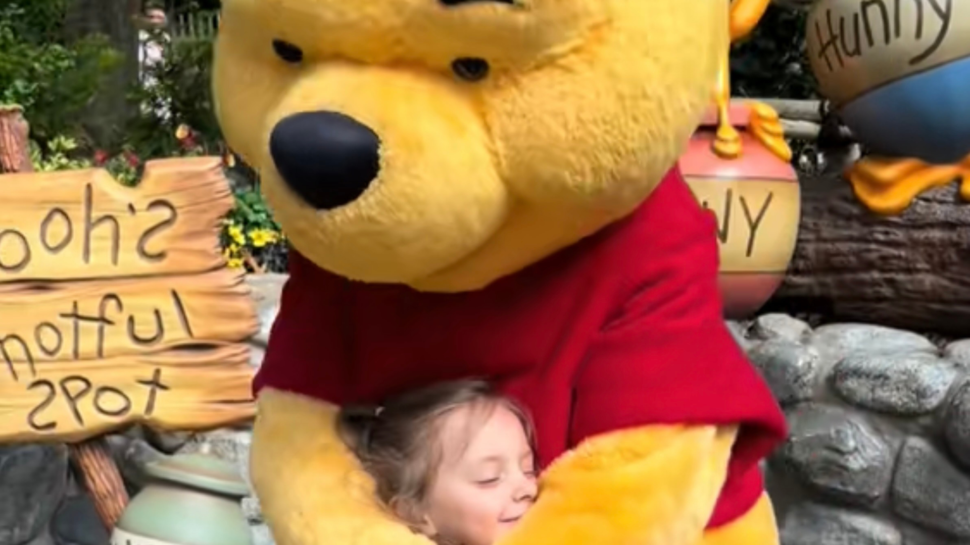 Winnie the Pooh hugs a smiling little girl