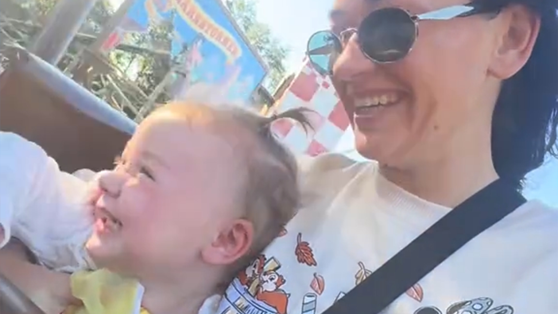A toddler with a big smile sitting on a woman's lap