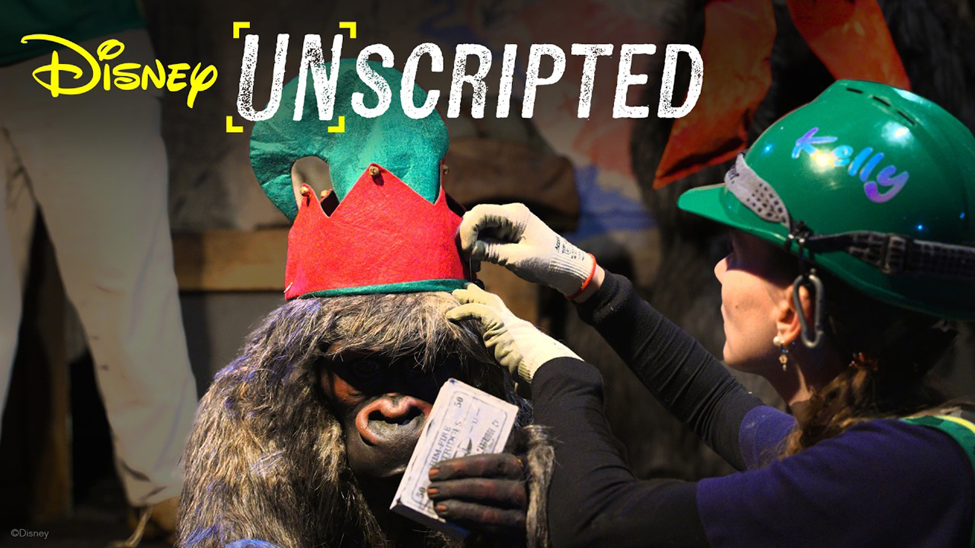 Disney Unscripted overlayed on a photo of a woman adjusting an elf hat on a monkey's head