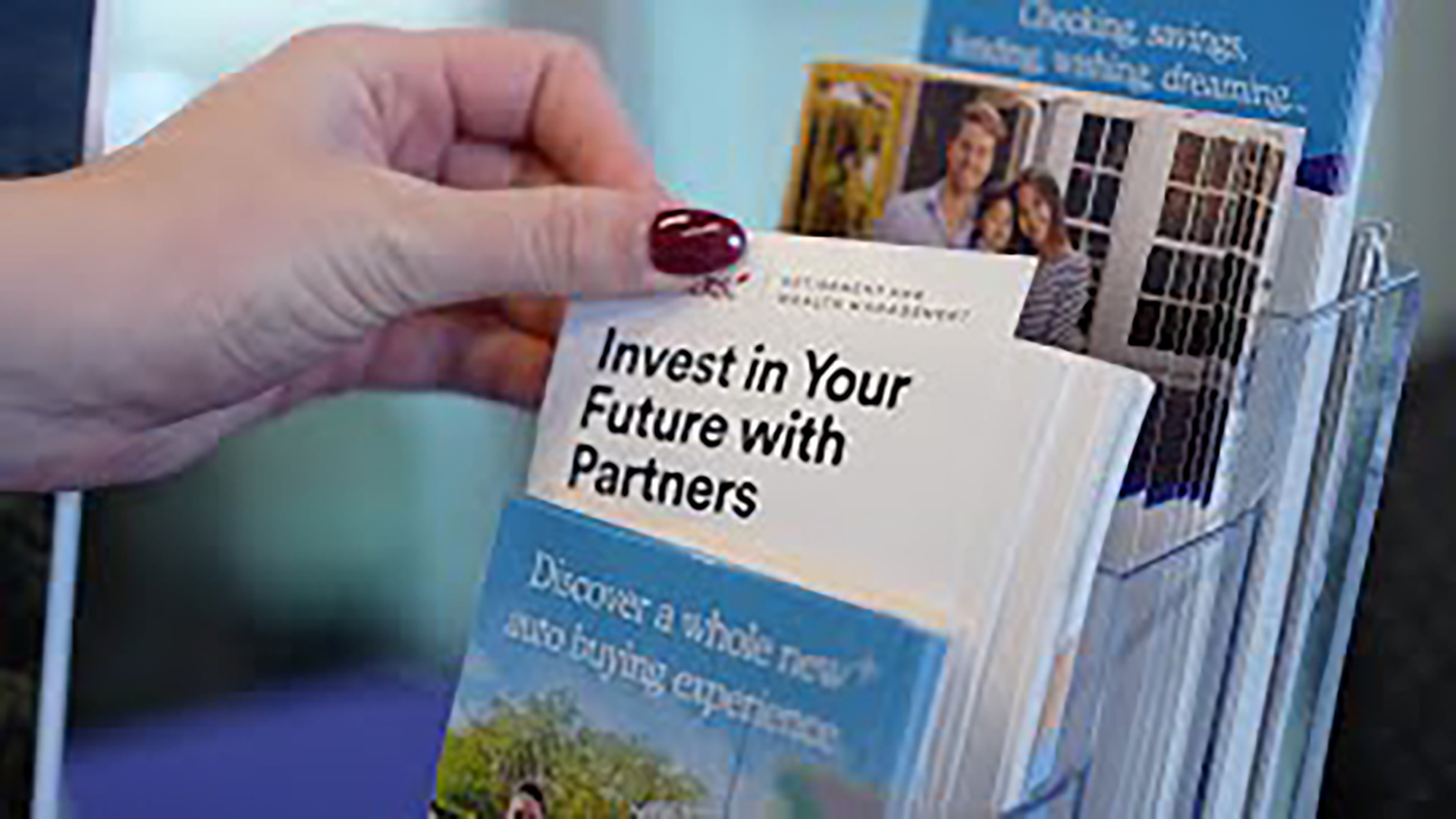 A hand lifts a brochure that reads "Invest in Your Future with Partners"