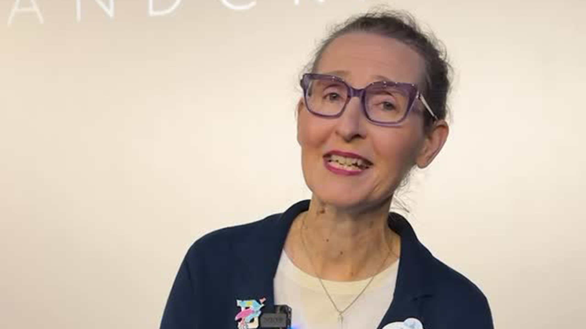 A woman with glasses smiles at the camera