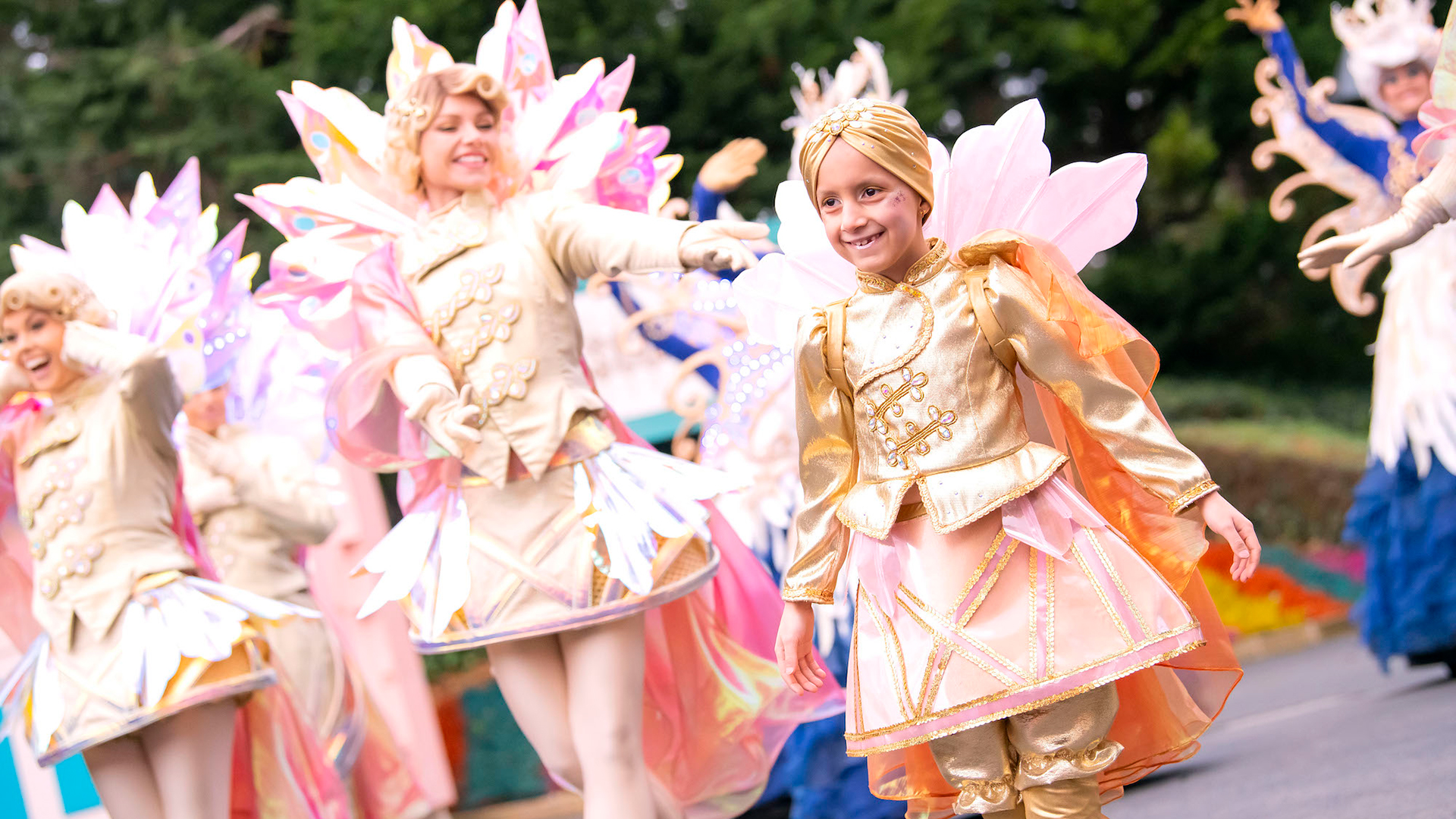 A young girl stands smiling in costume with parade performers