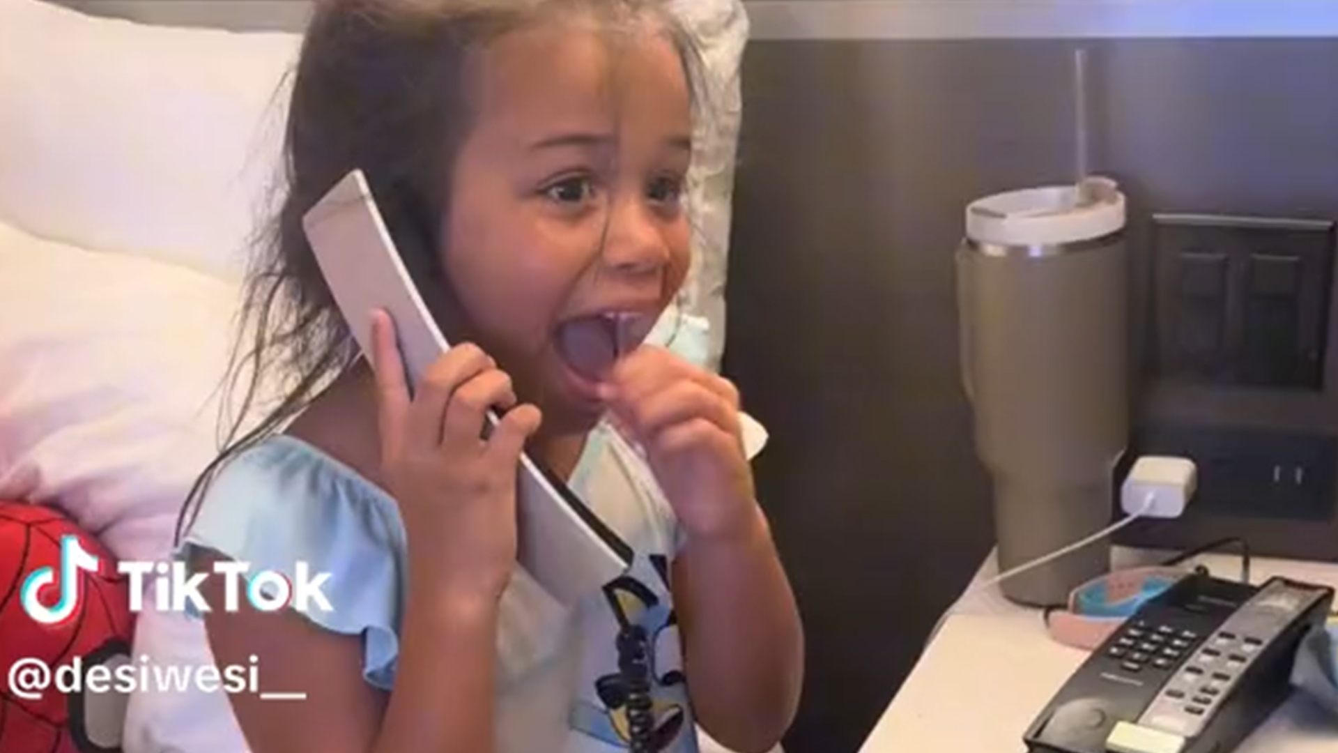 A young girl speaks on the phone with a surprised look on her face