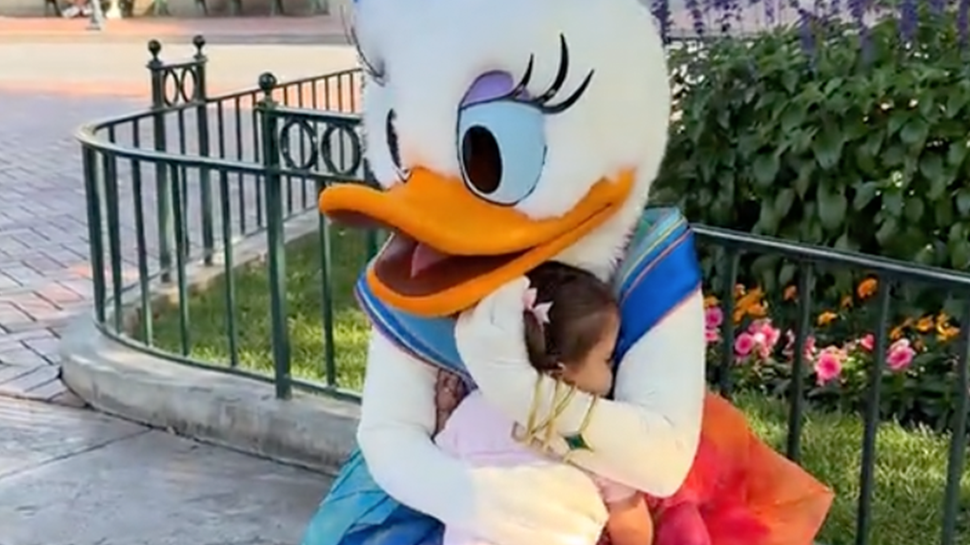 Daisy Duck hugs a young girl
