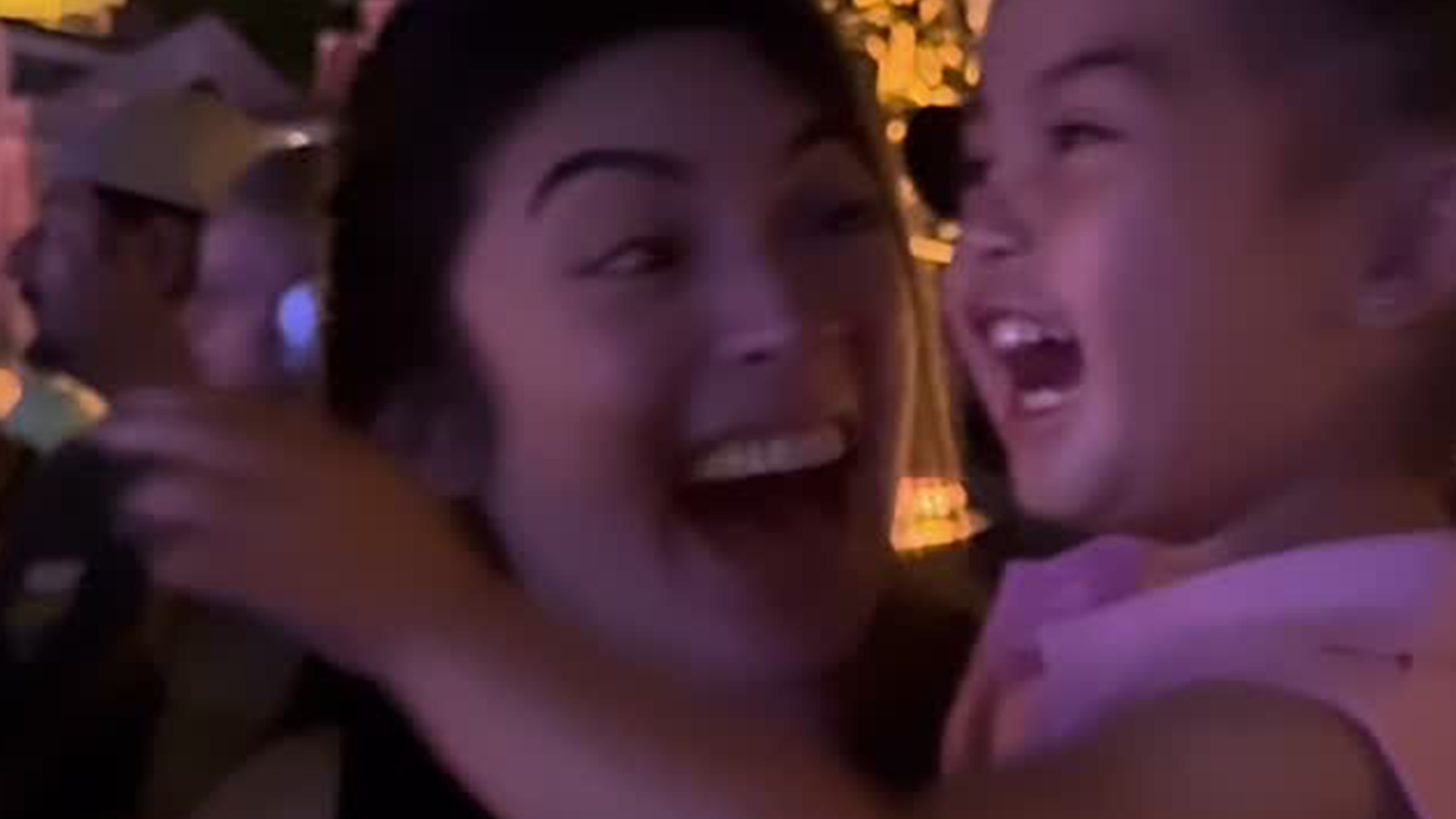 A young girl laughs as she watches a parade with her mother