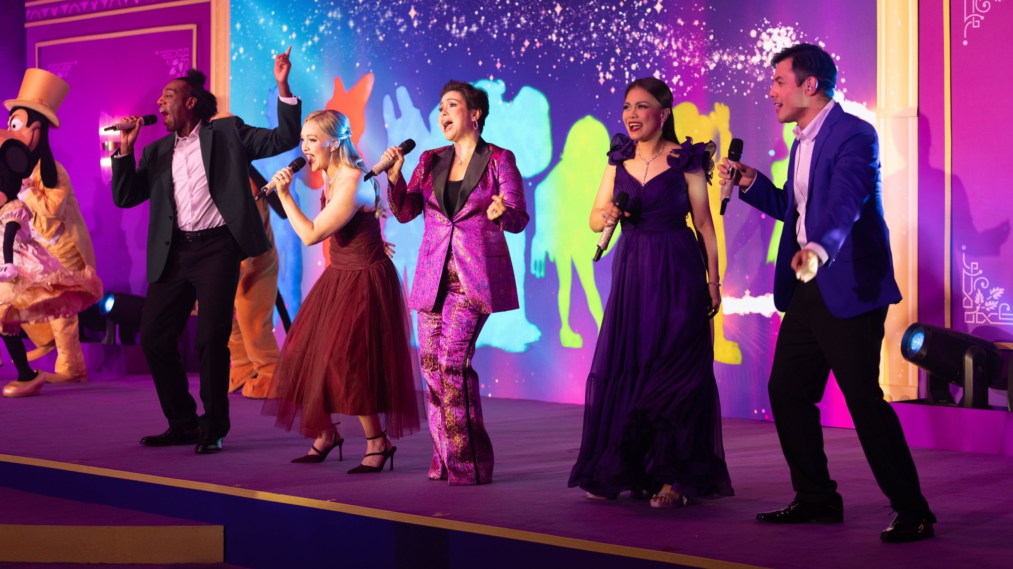 Group of singers performing on stage with Mickey & Friends