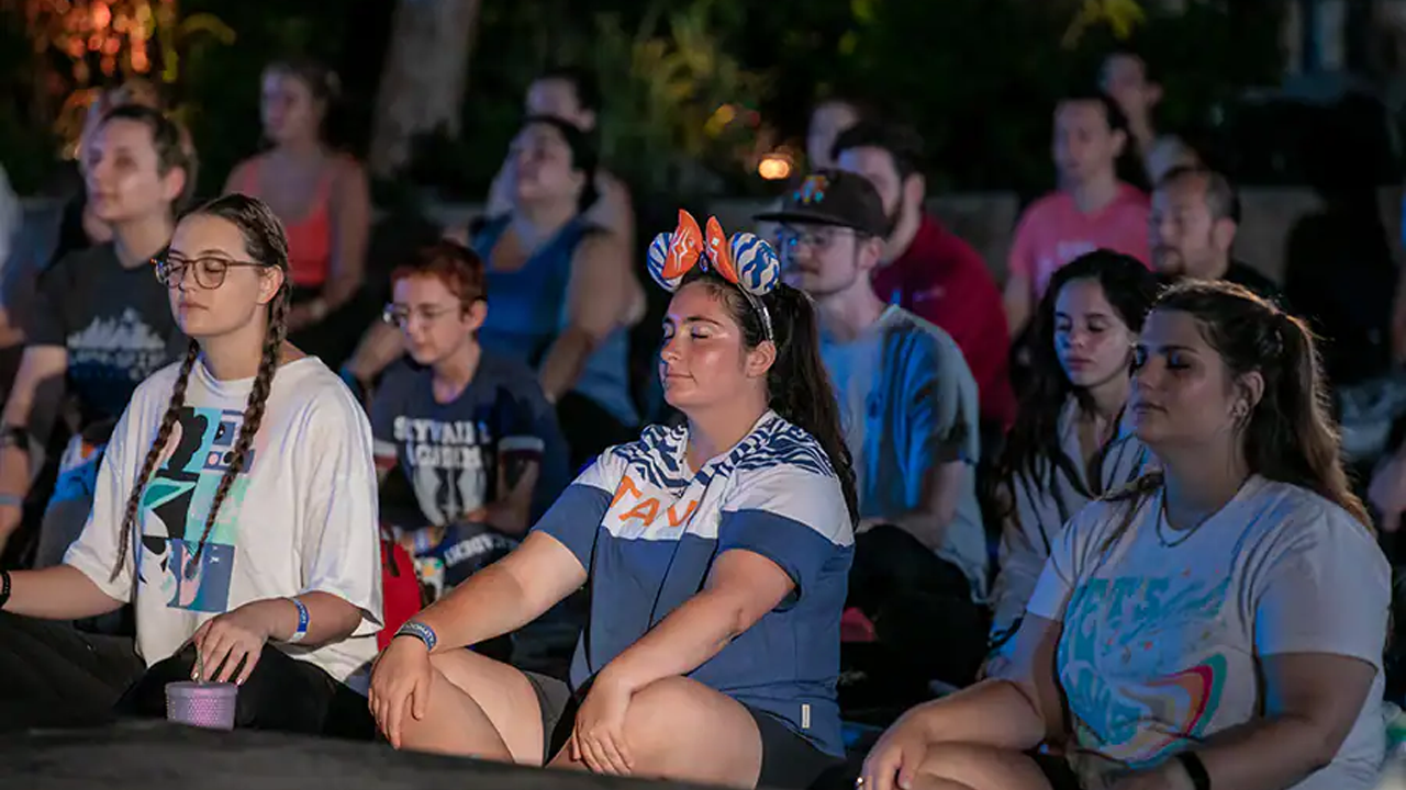 Cast Members sitting crossed leg at yoga. 