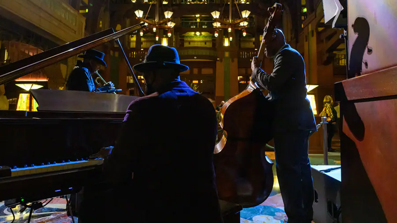Three men playing the trumpet, piano, and bass. 