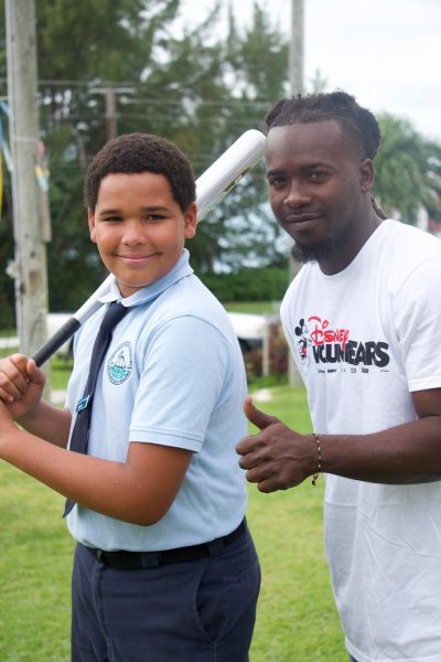 Disney volunteer stands with community member holding a baseball bat
