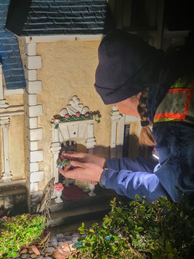 Resort Enhancement cast member, Ali Peale, installs a small wreath on Cinderella’s chateau in Storybook Land.