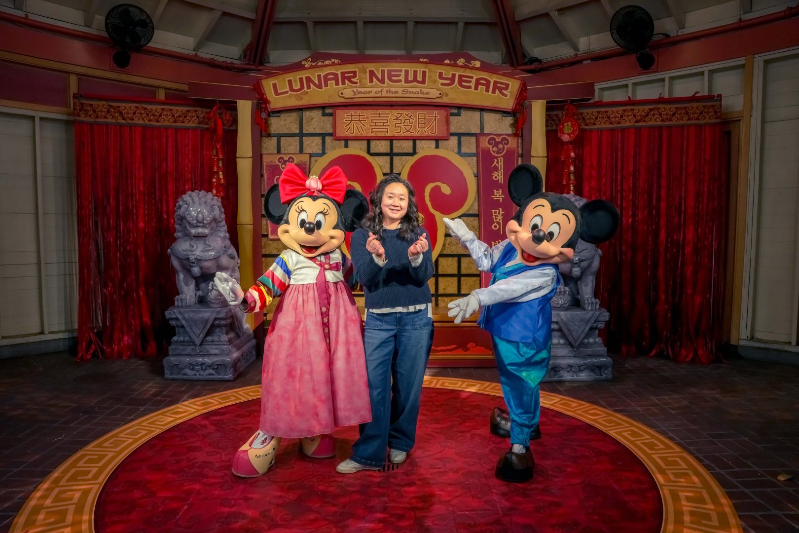 Cast member Grace Kang poses with Mickey Mouse and Minnie Mouse in their Lunar New Year costumes.