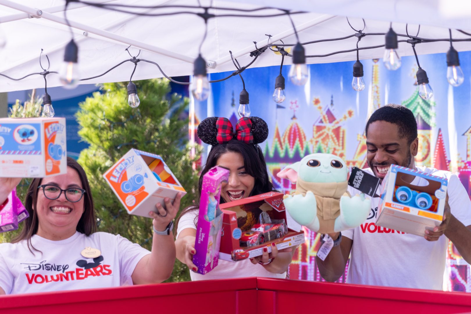 Former Disneyland Resort Ambassadors Nataly Guzman and Alexa Garcia, together with former Walt Disney World Ambassador Raevon Redding, excitedly add donations to a Toys for Tots bin.